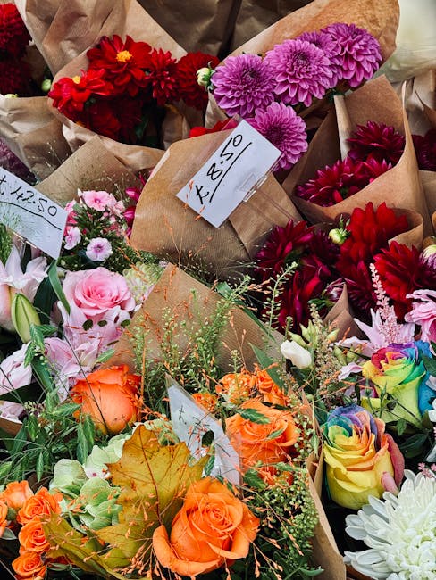 A colorful assortment of fresh flower bouquets displayed closely together, featuring a variety of blooms including vibrant red and pink dahlias, lavender-purple chrysanthemums, soft pink roses, multic