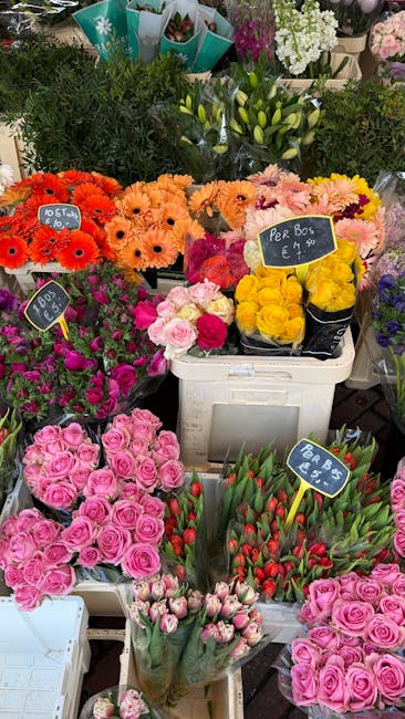 A colorful display of fresh flower bouquets at a flower market, featuring clusters of pink roses with lush, velvety petals, bright orange and pink gerbera daisies with cheerful, daisy-like blooms, and