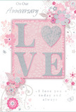 The anniversary card in this image is arranged against a soft background, its aesthetic reminiscent of an English spring garden tucked between elegant mansion blocks in Maida Vale. At the heart of the design, the word LOVE is spelled out in raised, softly shimmering glitter, giving a tactile presence that feels luxurious under the fingertips. The O is transformed into a silver, textured heart, its gleaming surface symbolising shared devotion and the emotional centre of the card. Around this focal point, a halo of delicate flowers opens in shades of blush, mauve, and pastel pink, their petals rendered with a gentle, almost watercolour wash. Fine outlines and pale shading give structure without heaviness, allowing the blooms to appear as though they are quietly unfolding across the card. Slender vines, swirling tendrils, and tiny decorative curls weave through the floral cluster, adding a sense of motion and grace. Small, subtle butterflies and scattered petal motifs are tucked between the larger elements, contributing touches of whimsy while maintaining the overall calm, romantic mood. The colour story leans on soft pastel pinks and silvery greys, complemented by hints of pearly white that add brightness without stark contrast. Elegant script phrases, including On Our Anniversary and I love you today and always, are written in flowing calligraphy that harmonises with the curves of the vines and leaves. The design feels intimate and heartfelt, like a carefully chosen card given after a stroll along the canal at Little Venice, paired with a bouquet of pastel blooms. It offers a quiet but deeply sincere way to mark a shared journey of love over the years.